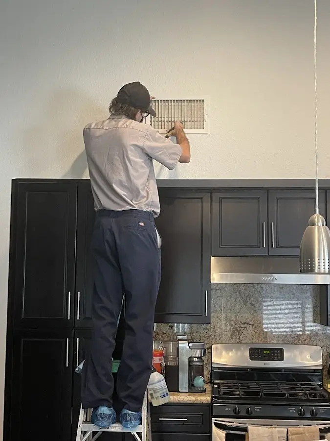 Technician inspecting an air vent during HVAC service in La Joya